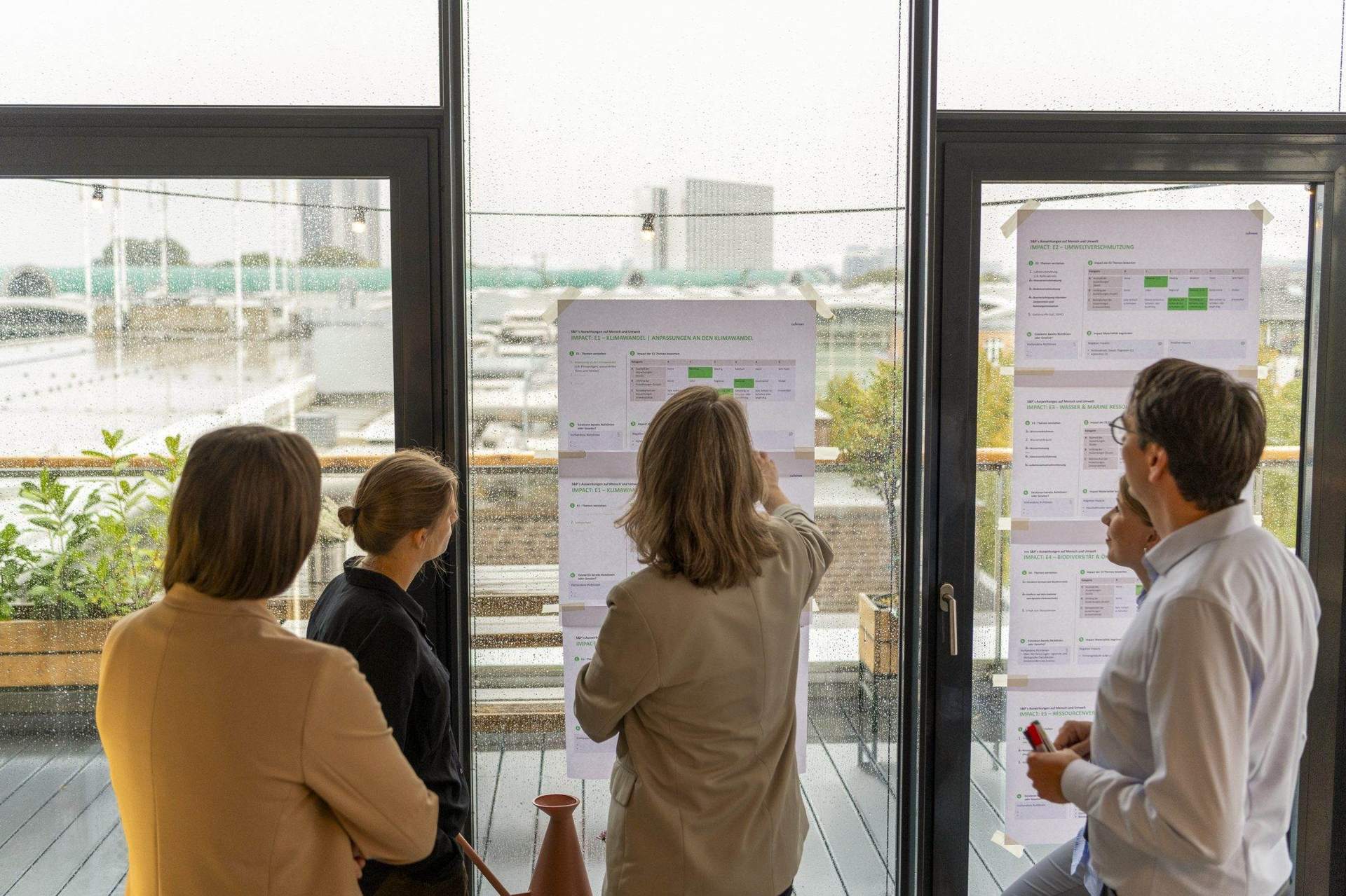 Drei Personen arbeiten an Stellwänden vor einer Fensterfront