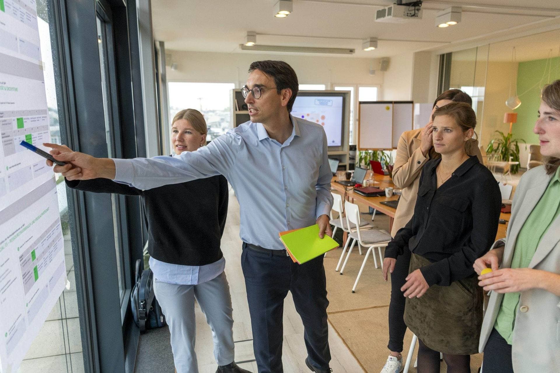 Berater von transformis zeigt auf eine Wand, das Team schaut zu