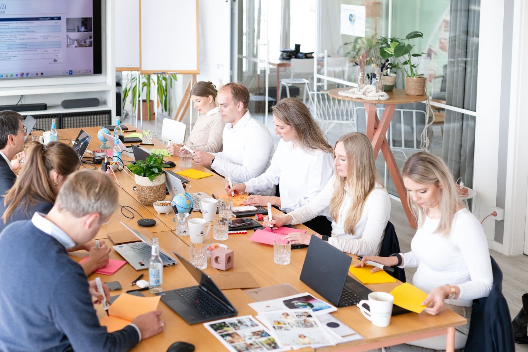 Lange Arbeitstafel mit Laptops und Unterlagen in einem Workshop
