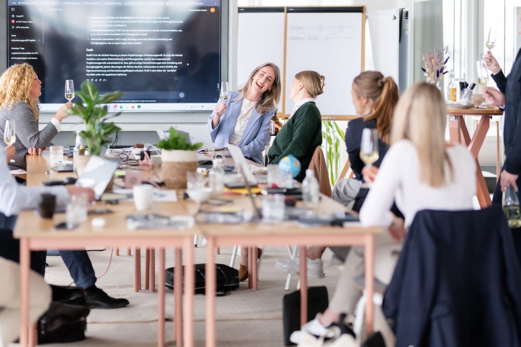 Workshop-Plenum an langen Tischen vor einer Präsentationswand